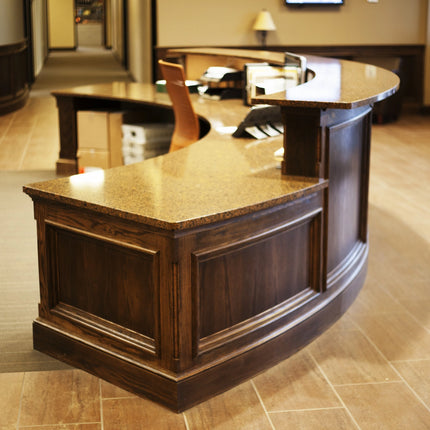 Wooden radius reception desk with quartz countertop in a lobby setting