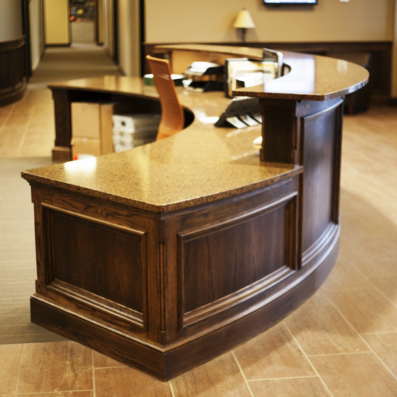 Wooden radius reception desk with quartz countertop in a lobby setting