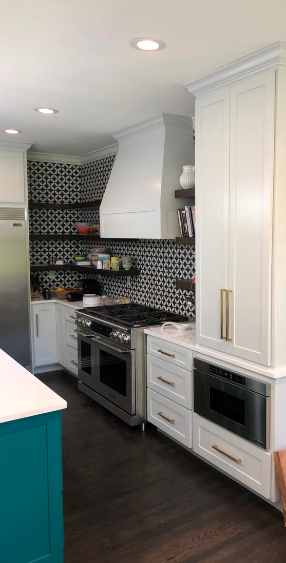 Modern kitchen with white cabinets, stove, and patterned backsplash.