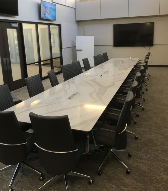 White marble conference table with black chairs in a modern office setting