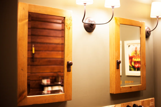 Wooden medicine cabinets on a wall with light fixture above