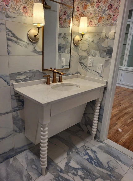 Vanity with custom turned legs and quartz countertop in a tiled bathroom