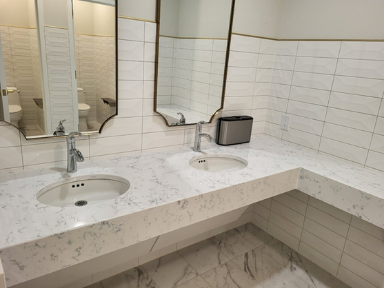 Bathroom with double sink vanity with mitered front aprons and tiled walls